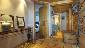 Un pasillo con paredes de madera y suelo de baldosas que conduce a un dormitorio con cama y mesita de noche.