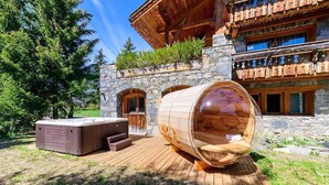 Una bañera de hidromasaje de madera y un jacuzzi frente a un edificio de piedra con balcones de madera.