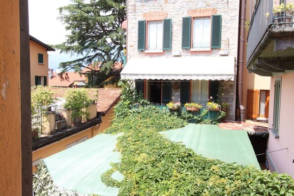 A courtyard with a stone building, green shutters, and potted plants.