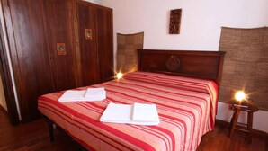 A hotel room with a large bed, wooden wardrobe, and a small bedside table with a lamp. - Captivating 4 -bed Apartment in Bellagio Historic (Bellagio)
