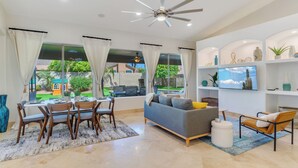 A modern living room with a dining area, a sofa, a TV, and a ceiling fan. - Central Scottsdale w/heated pool, BBQ, EV charging (Scottsdale)
