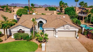 A residential house with a garage, a swimming pool, and a well-maintained lawn. - Central Scottsdale w/heated pool, BBQ, EV charging (Scottsdale)