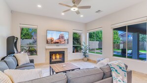 A living room with a fireplace, a ceiling fan, and large windows. - Central Scottsdale w/heated pool, BBQ, EV charging (Scottsdale)