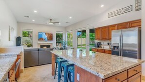 A modern kitchen with granite countertops, stainless steel appliances, and a large island with bar stools. - Central Scottsdale w/heated pool, BBQ, EV charging (Scottsdale)