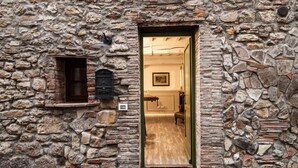 Un edificio de piedra con puerta de madera, una ventana pequeña y un cuadro en la pared.