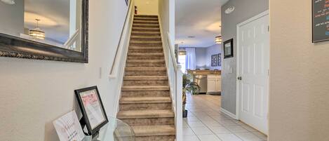 A staircase leading to a second floor, a framed certificate on a glass table, and a door with a sign.