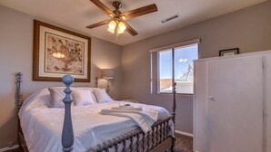 A bedroom with a four-poster bed, a ceiling fan, a window with a view, and a wardrobe. - This One's Better-More To Do-More Modern-More Fun!!! (Prescott Valley)
