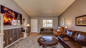 A living room with a fireplace, a sofa, a coffee table, and a TV mounted on the wall. - This One's Better-More To Do-More Modern-More Fun!!! (Prescott Valley)