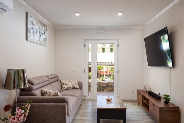 A living room with a sofa, coffee table, TV, and a door leading to an outdoor area.