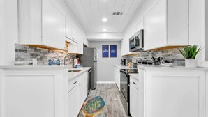 Una cocina moderna con armarios blancos, un microondas y una isla central.