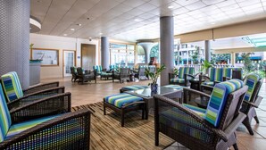 A spacious lobby with wicker furniture and a central coffee station.