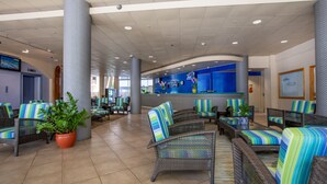 A lobby with wicker furniture, potted plants, and a reception desk.