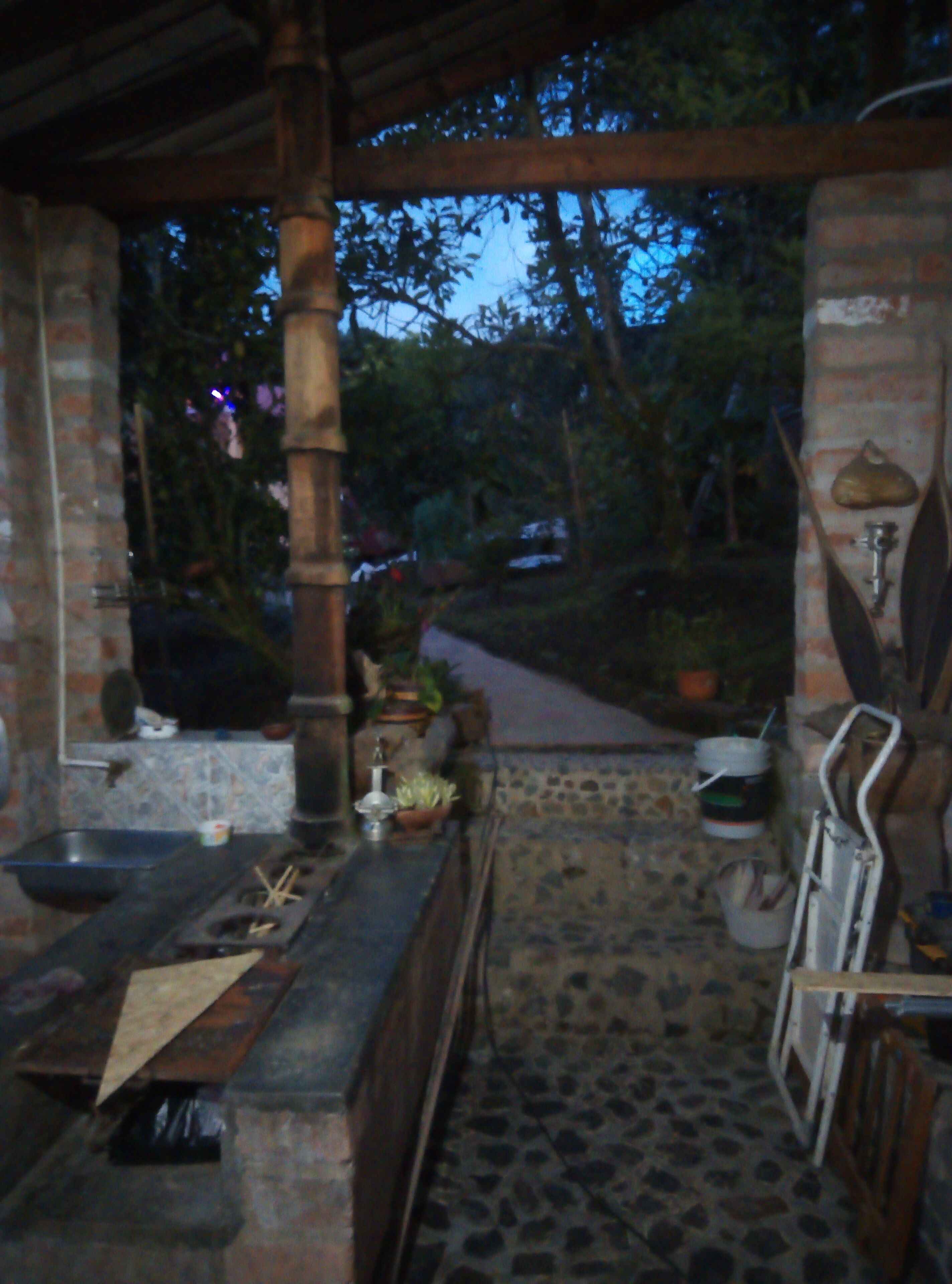 An outdoor kitchen area with a stone floor, a brick wall, and a wooden pergola.