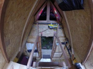 Un intérieur en bois avec un plafond en pente, une échelle et une fenêtre.