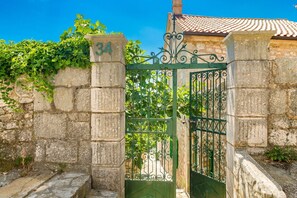 Traditional stone gate with ornate metalwork, set within a stone wall, offering a glimpse into the property's rich history.