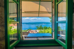 Enjoy a panoramic view of the coast from this room's large window, featuring a blue table on a brick ledge.