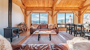 A cozy living room with a fireplace, leather sofa, and a dining area with chairs and a table.