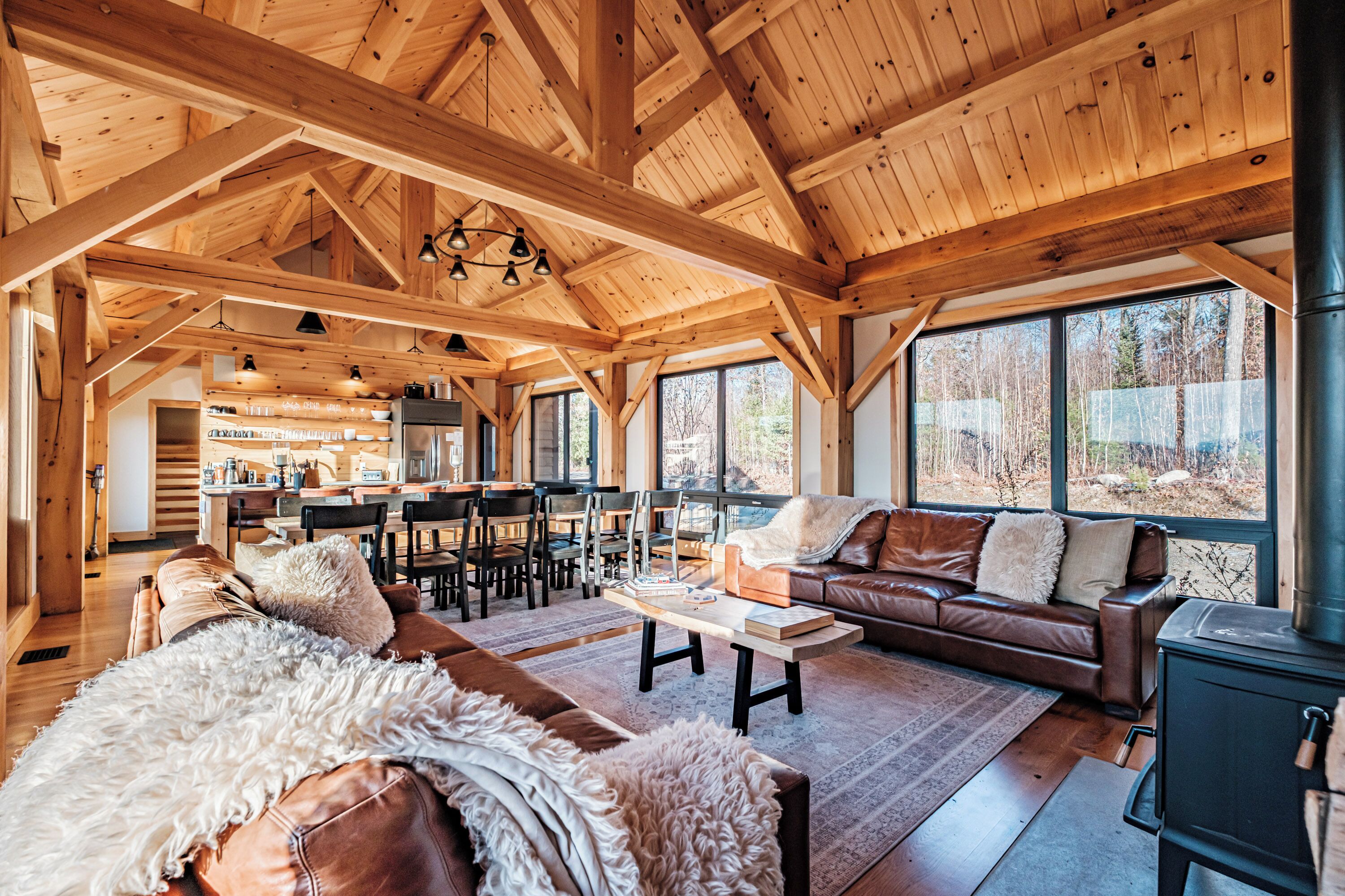 Un vaste espace de vie agrémenté d’un grand plafond en bois, d’une cheminée chaleureuse et offrant une vue sur l’extérieur grâce à de grandes fenêtres.