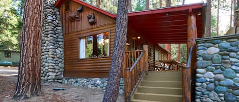 Une cabane avec des fondations en pierre, un revêtement extérieur en bois et un escalier menant à un porche abrité.