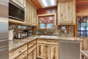 A kitchen with wooden cabinets, a granite countertop, a built-in microwave, a coffee maker, and a window. - (52) Tuolumne Meadow (1 Bedroom Only) at The Redwoods In Yosemite (Yosemite National Park)