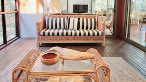 A spacious room with a large window, a wicker sofa, and a woven coffee table.