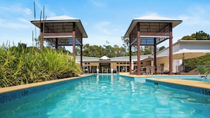A swimming pool with a 1.5m depth marker, surrounded by a covered area with two wooden structures.