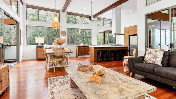 A spacious living area with a wooden dining table, a sofa, and a kitchen with a large island.
