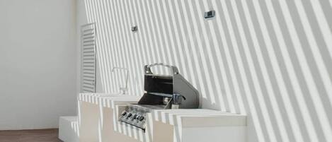 A modern, minimalist room with a sloped ceiling and a built-in grill station.