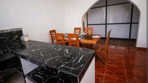 Una cocina con encimera de mármol, sillas de madera y una mesa de comedor.
