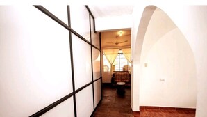 Un pasillo estrecho con piso de madera, paredes blancas con detalles negros y un ventilador de techo.