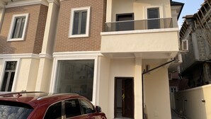 Une maison à deux étages avec un balcon, un garage et un chantier de construction situé à proximité.