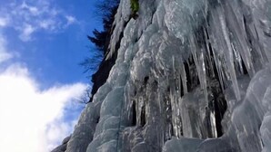 Une grande formation de glace sur laquelle une personne est en train de grimper.