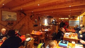 Un intérieur en bois avec des tables et des chaises, un coin bar et une fresque murale.