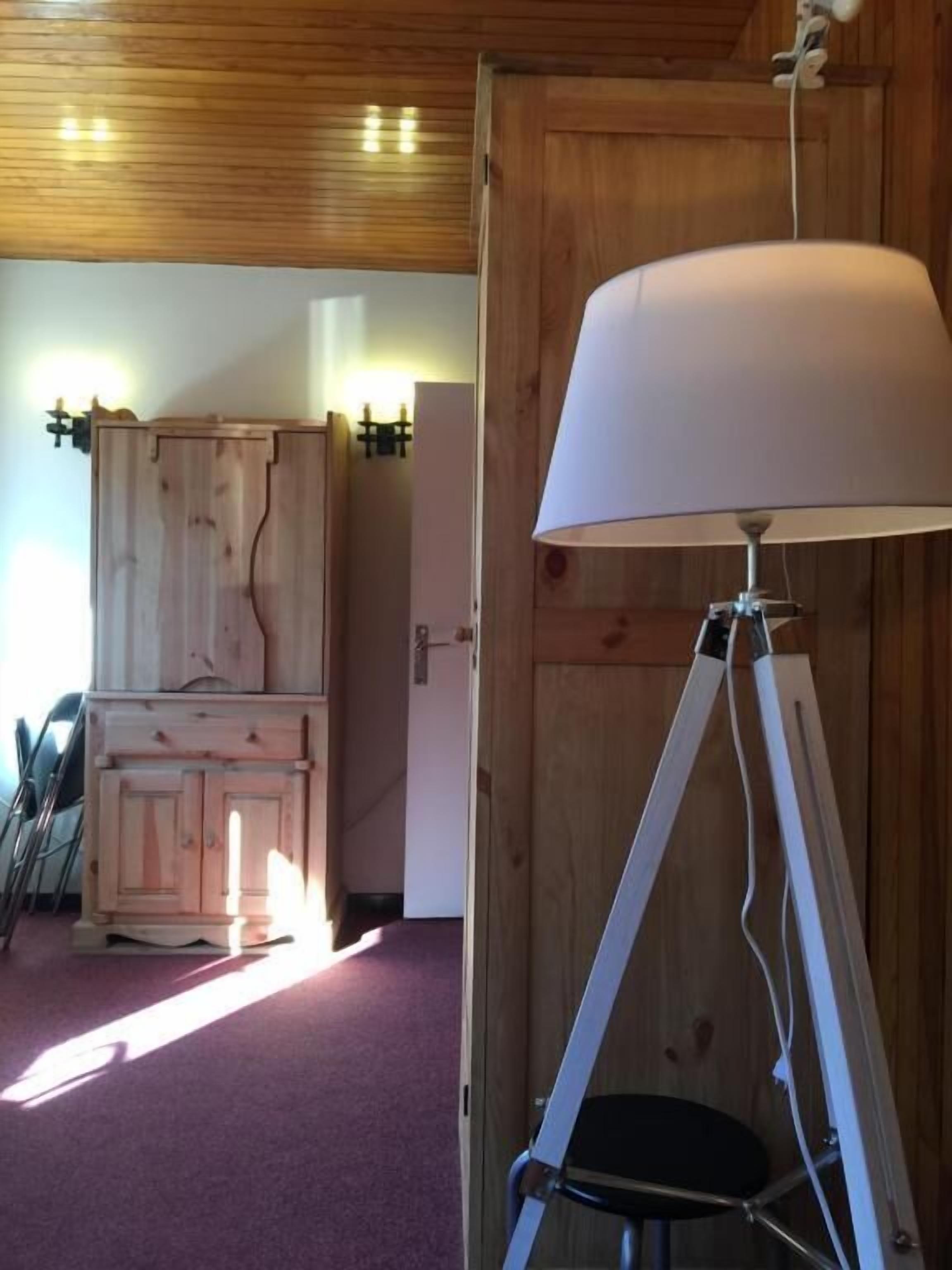 A room with a wooden cabinet, a lamp on a tripod stand, and a purple carpet.
