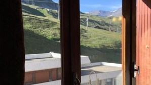 Une chambre avec vue sur des collines verdoyantes et une chaîne de montagnes.