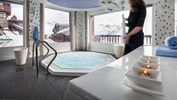 Une salle de spa équipée d’un bain à remous, d’une table de massage et de bougies.