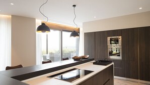 Een moderne keuken met een centraal eiland, donker houten kastjes, een inbouwmagnetron en hanglampen.