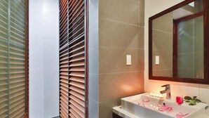 A bathroom with a wooden slatted partition, a mirror, and a sink with candles.