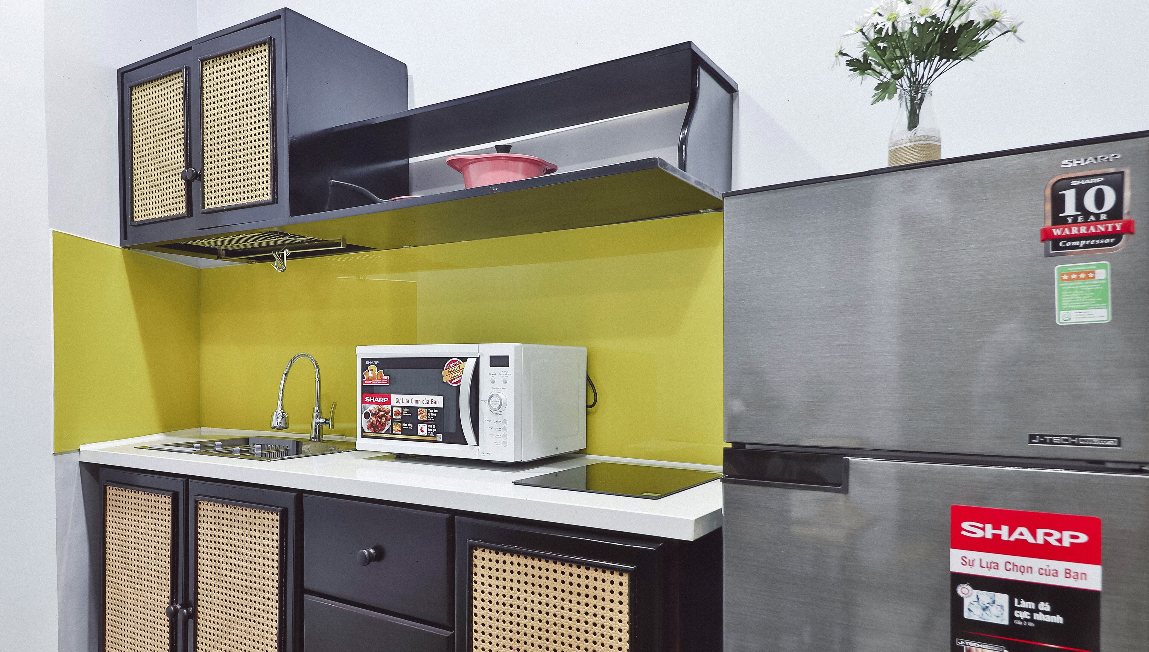 A compact kitchen with a microwave, sink, and a refrigerator.