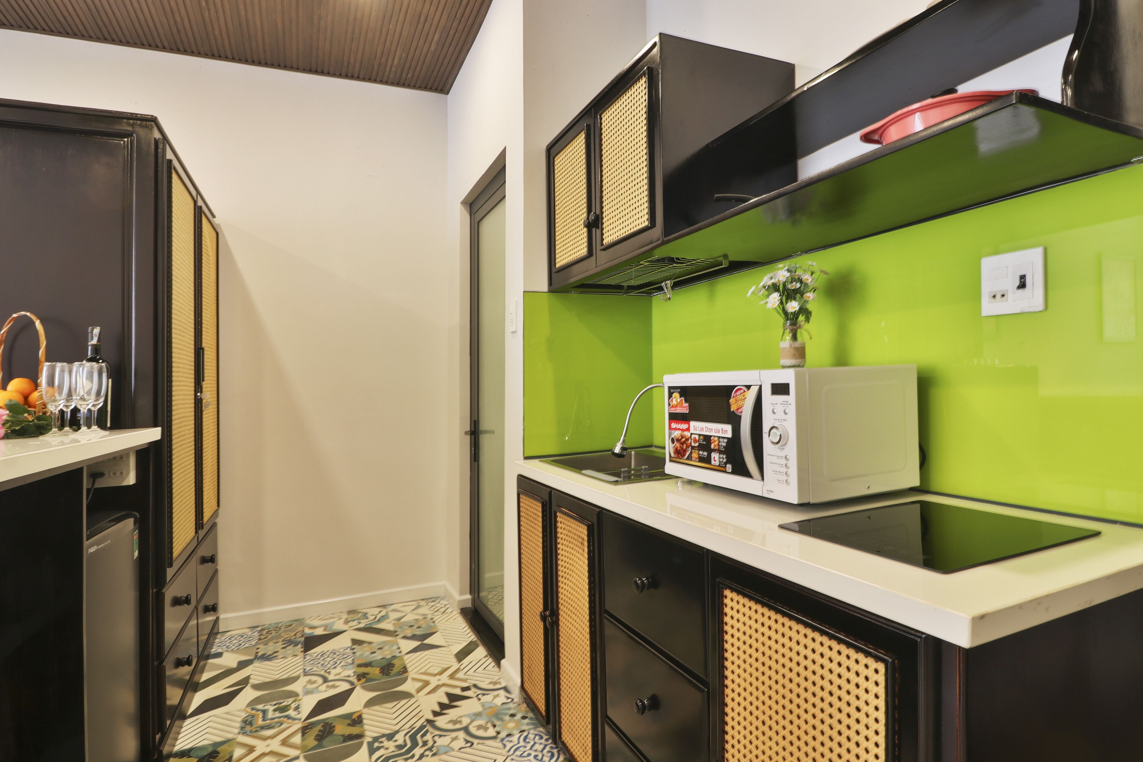 Cozinha compacta com micro-ondas, pia e piso estampado.