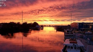 Un bateau était amarré dans une marina au moment du coucher du soleil, et l’eau, calme, reflétait le ciel.