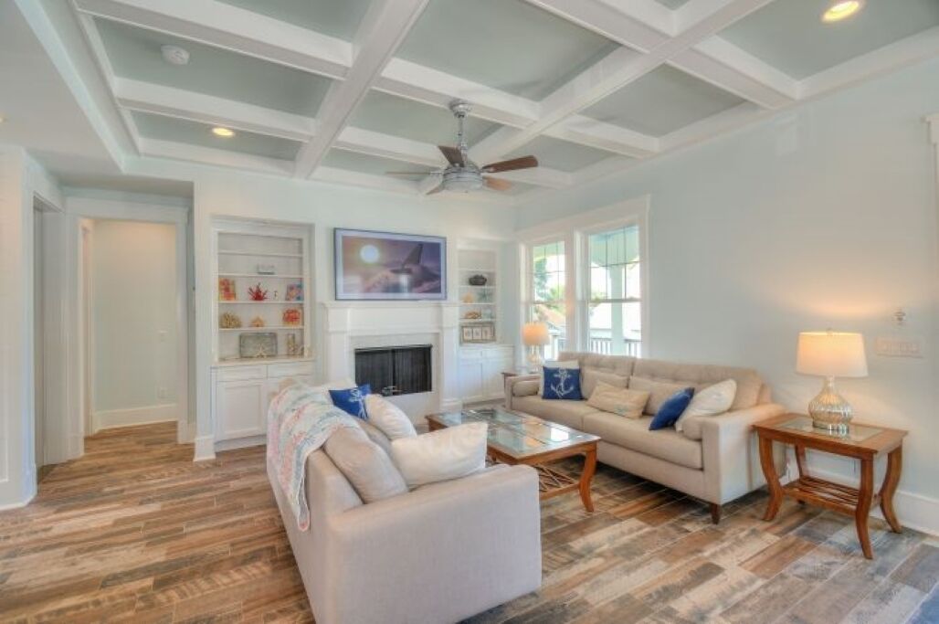 A spacious living room with a fireplace, two sofas, a coffee table, and a ceiling fan.