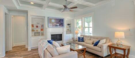 A spacious living room with a fireplace, two sofas, a coffee table, and a ceiling fan.