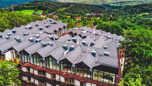 En byggnad med flera våningar, en rad balkonger och utsikt över ett bergigt landskap.