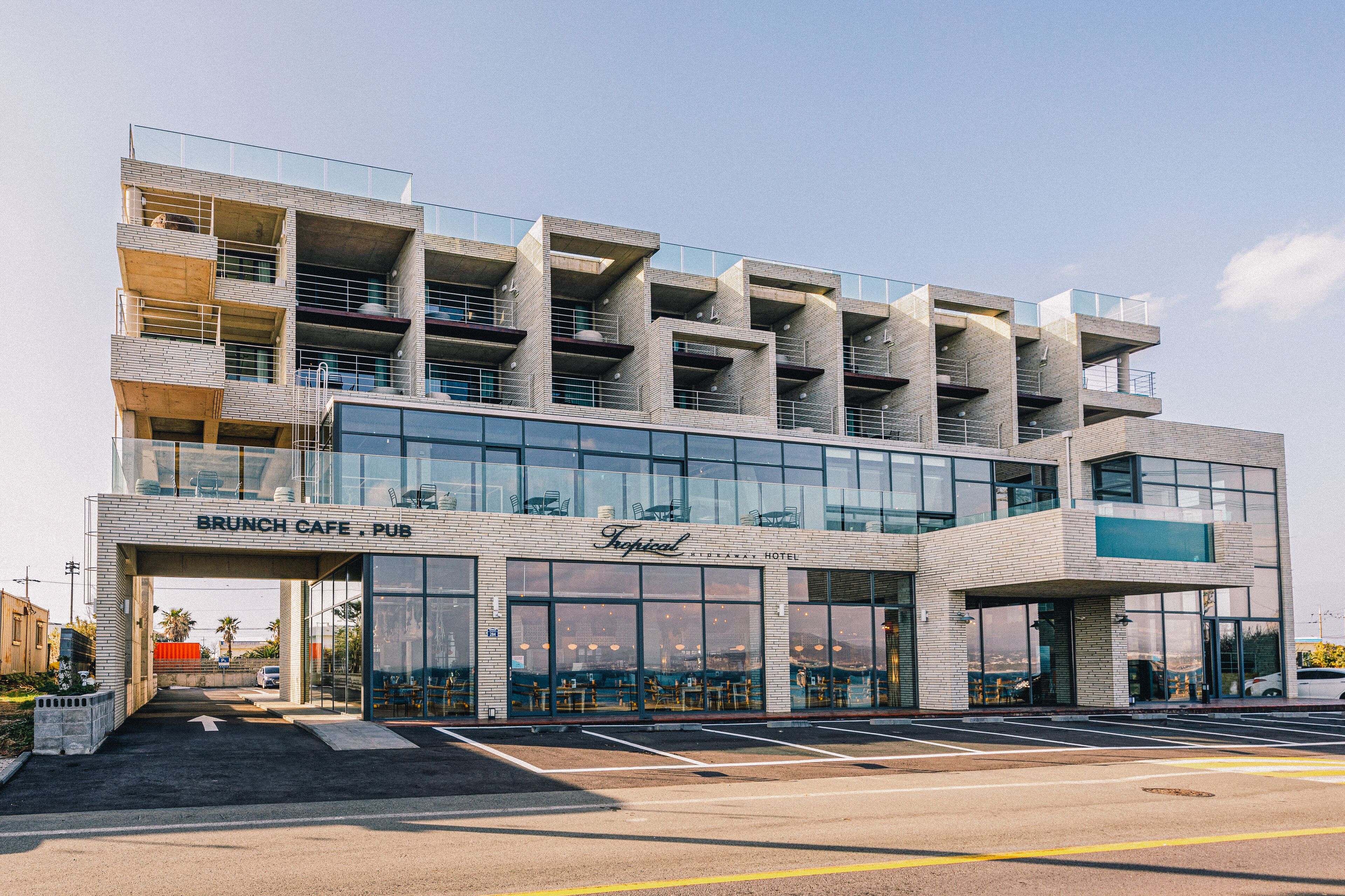 A modern building with a 'Brunch Cafe' and 'Pub' sign, featuring a glass facade and multiple balconies.