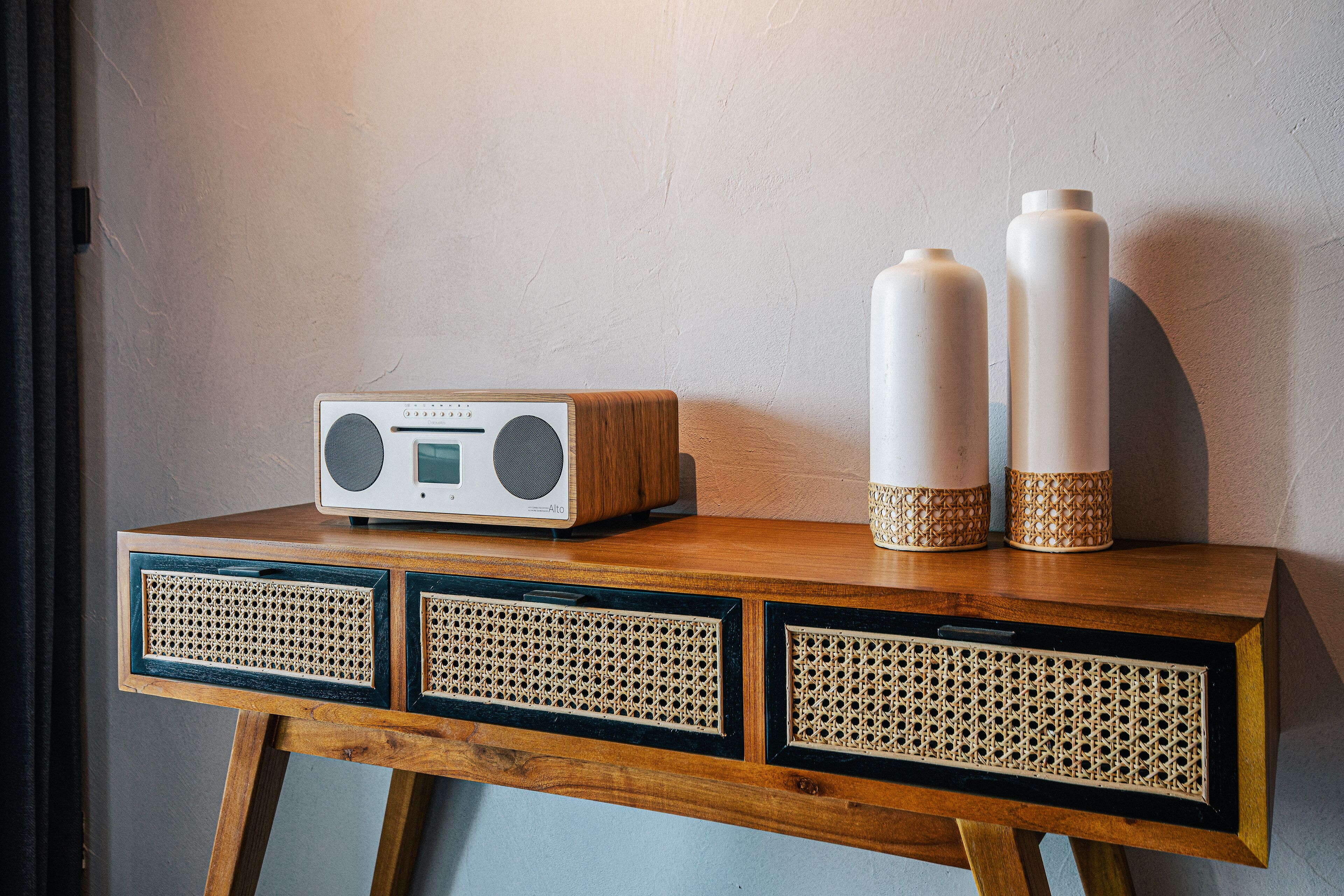 Une table en bois avec une radio, deux vases et trois tiroirs.