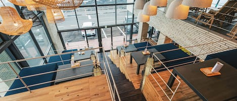 A modern interior with a view of the ocean through large windows, wooden flooring, and multiple seating areas.