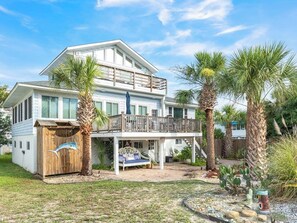 A two-story house with a balcony, a covered patio, and a small boat sculpture.
