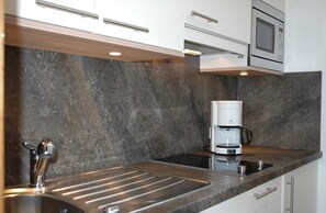A modern kitchen with a built-in microwave, coffee maker, and stainless steel sink.