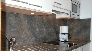 Eine moderne Küche mit Einbau-Mikrowelle, Kaffeemaschine und Spüle aus Edelstahl.